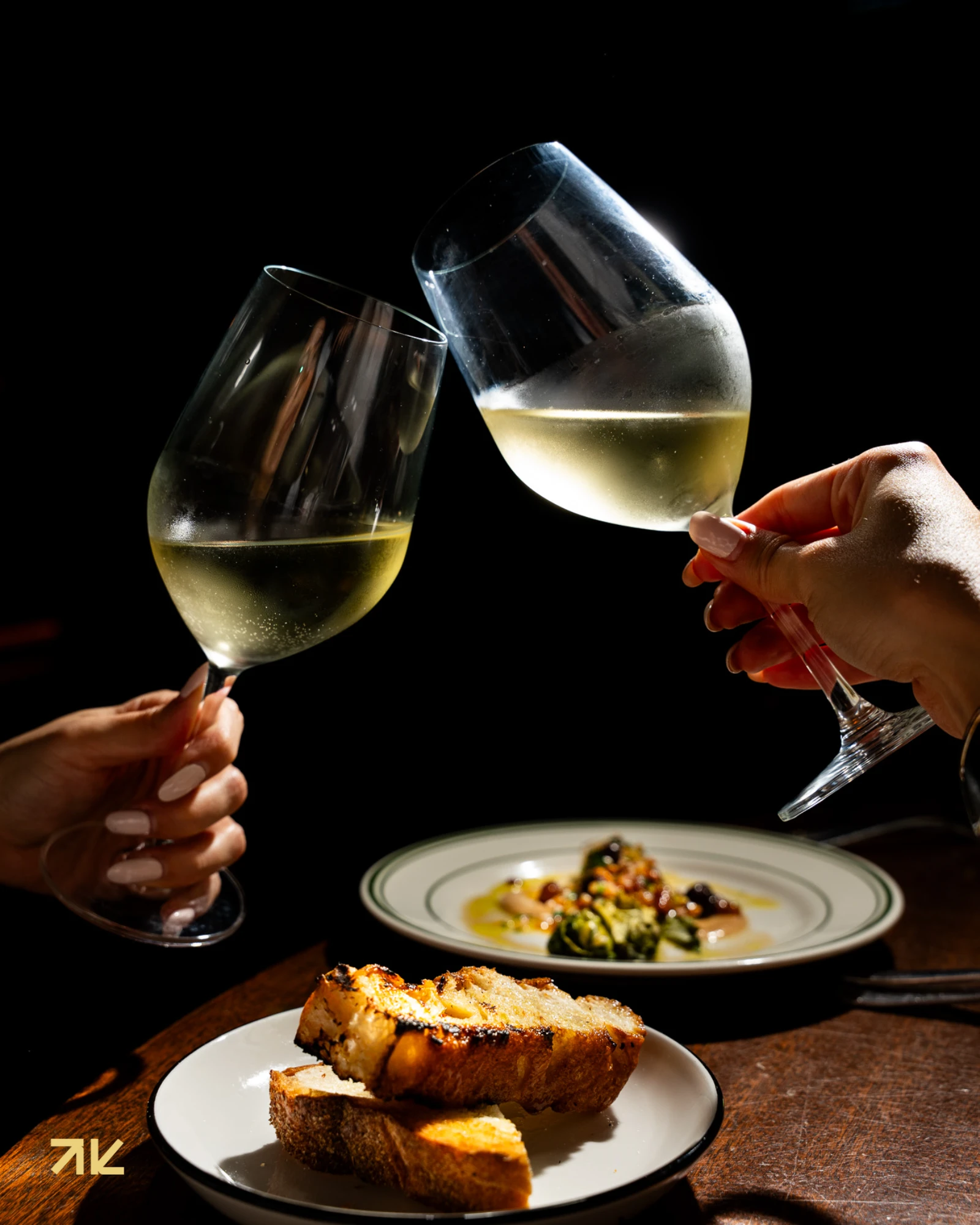 Dos copas de vino chocando sobre una mesa de Macchialina